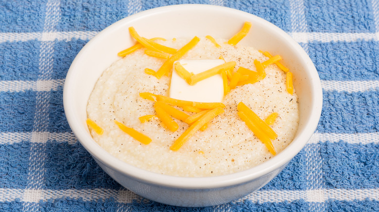 Top view of bowl of grits topped with shredded cheddar and butter