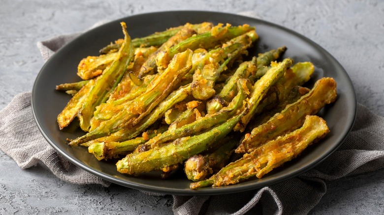 Crispy, golden okra fries on a black plate