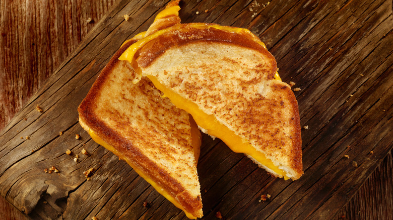 Halved grilled cheese sandwich on wooden board