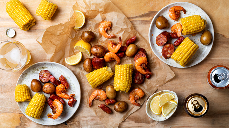 Top view of boiled shrimp, sausage, baby potatoes, corn, and lemon slices