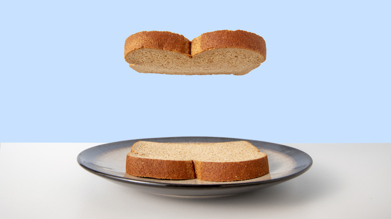 One slice of bread floating over another that rests on a plate
