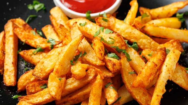 Crispy french fries with ketchup nearby close up