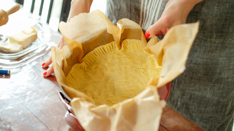 Woman holding springform pan with docked pie crust inside
