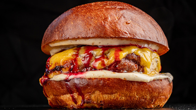 A closeup of a juicy burger with cheese on a bun