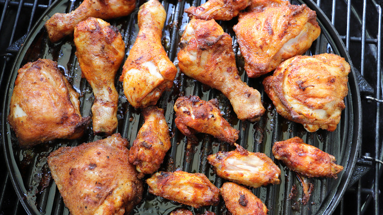 Different cuts of chicken cooking on the grill