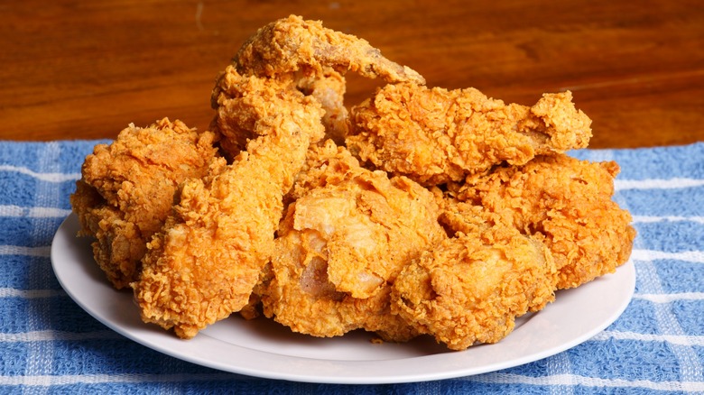 Crispy fried chicken on white plate sitting on blue and white towel