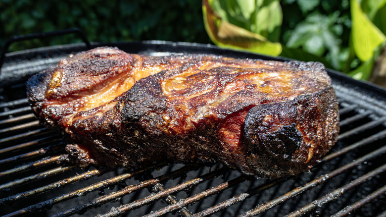 A large cut of cooked pork butt on a grill