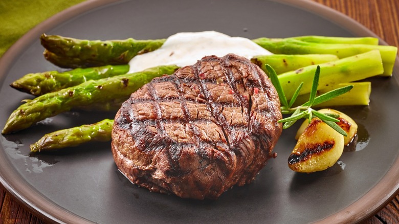 Grilled filet mignon on a plate with asparagus and roasted garlic