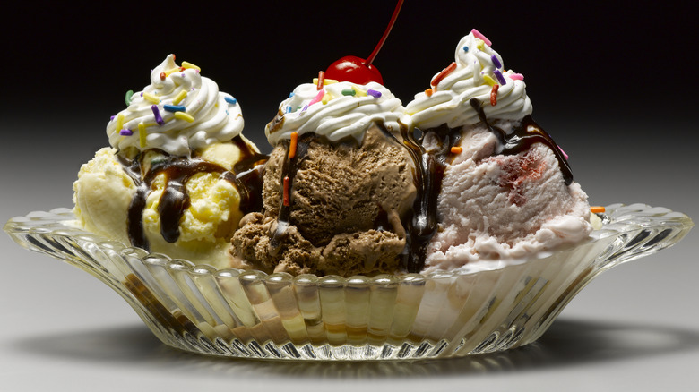 A three scoop ice cream sundae in a glass bowl