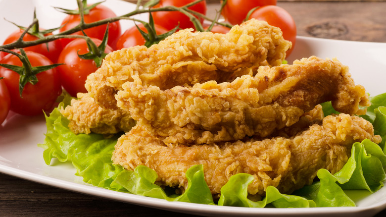 A plate of chicken strips with tomatos