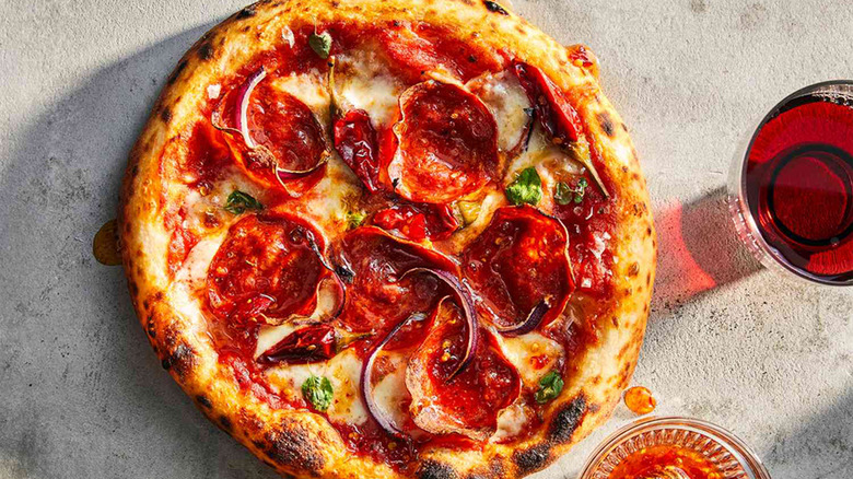 A pizza with soppressata onions, basil, and Calabrian chiles