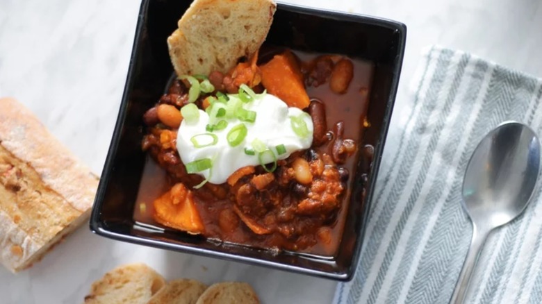 Chili with bread, dollop of sour cream, and spoon to the side