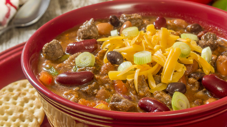 Red bowl of venison chili with beans and cheese