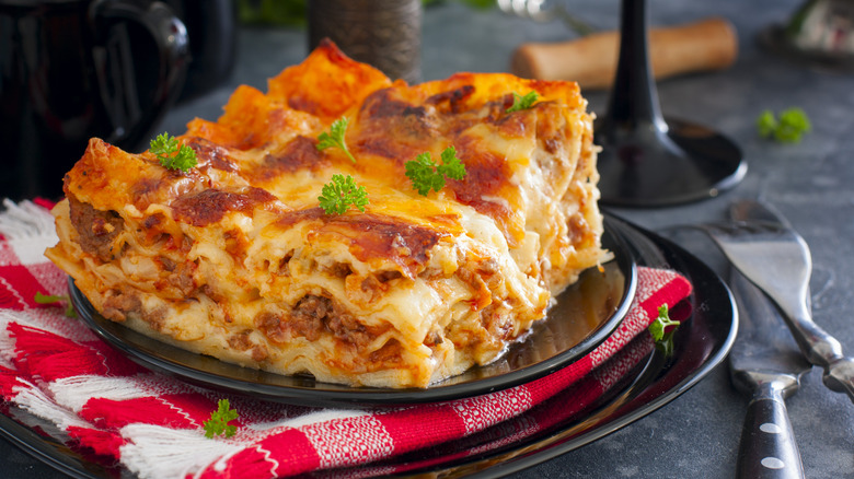 A slice of lasagna on a black plate