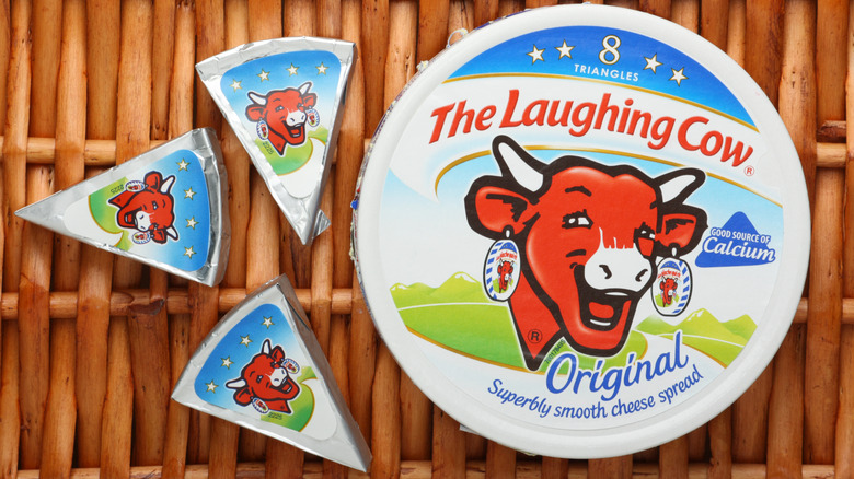 Laughing Cow cheese wedges next to a package on top of a wicker woven surface.