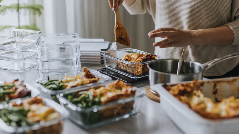 A person meal prepping and measuring out cooked food in tubs
