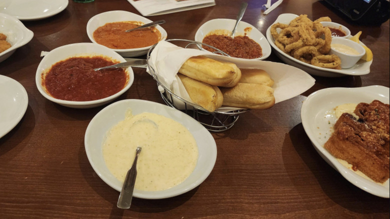 Olive Garden breadsticks on table with dipping sauces, calamari, and lasagna fritta.