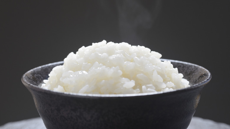 Steaming Japanese rice served in a small black bowl.