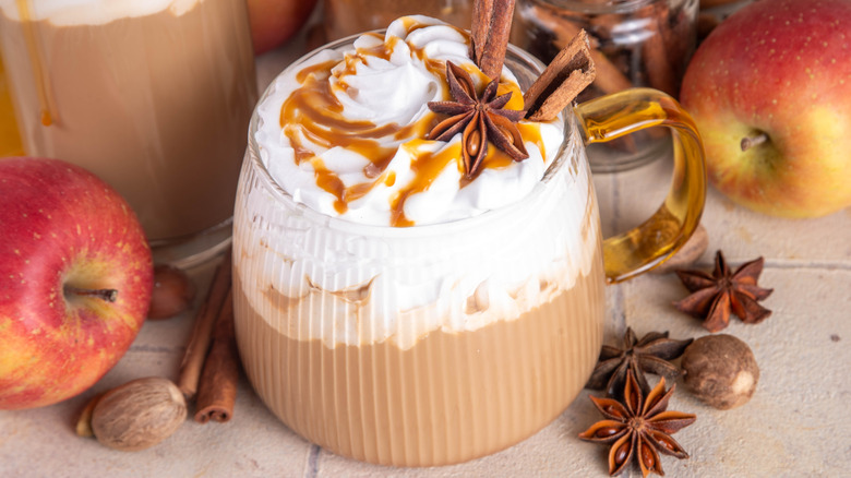 Latte with spices on top along with apples on the side.