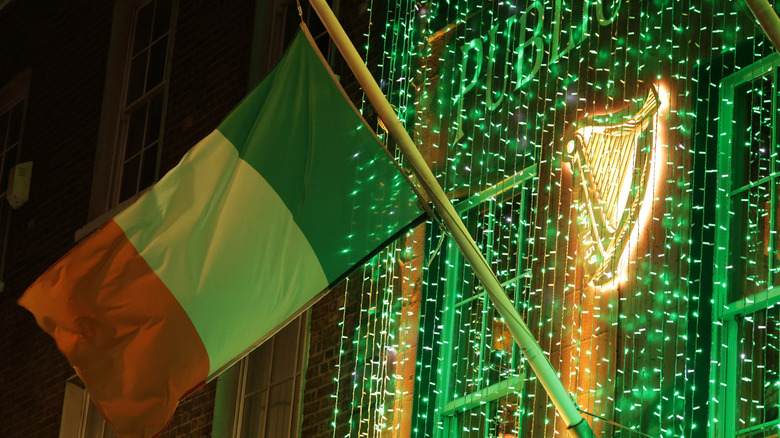 The Irish flag waving in front of green Christmas lights and the Guinness harp logo