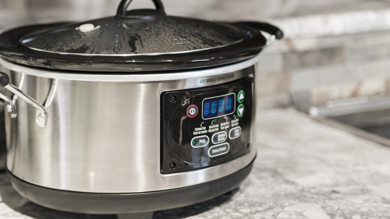 A turned on slow cooker on a countertop.