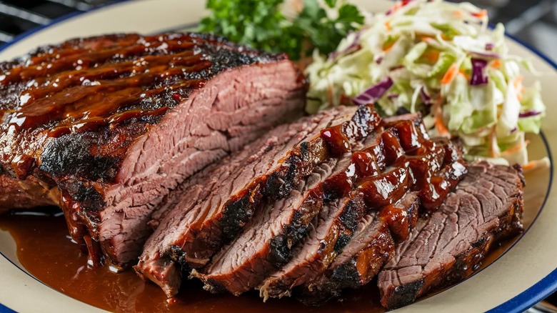 Sliced beef brisket and coleslaw on white plate