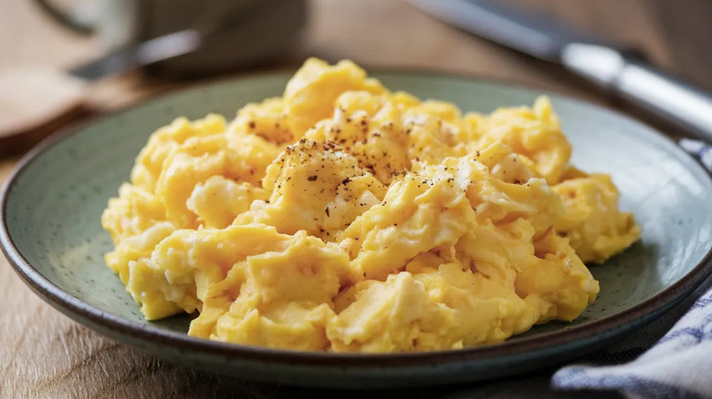A plate of fluffy scrambled eggs with seasoning on them