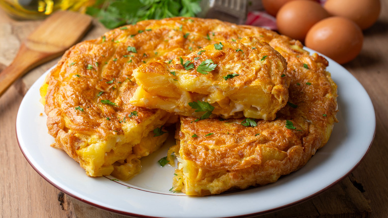 A Spanish omelet sitting on a plate with one slice cut out and sitting on top.