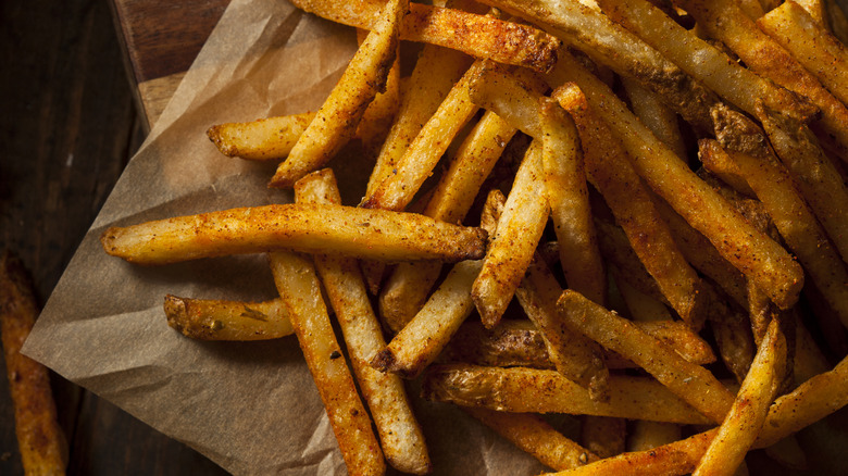 Close up of crispy seasoned fries on parchment paper