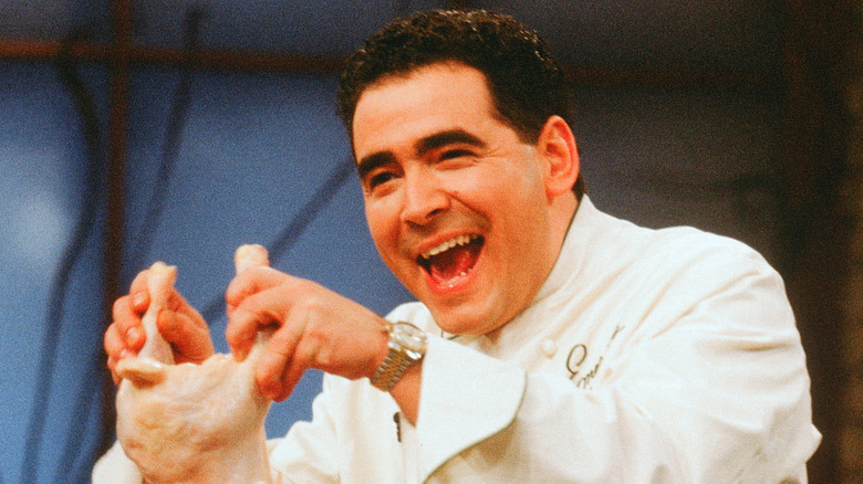Emeril Lagasse smiling and holding up a chicken on Emeril Live