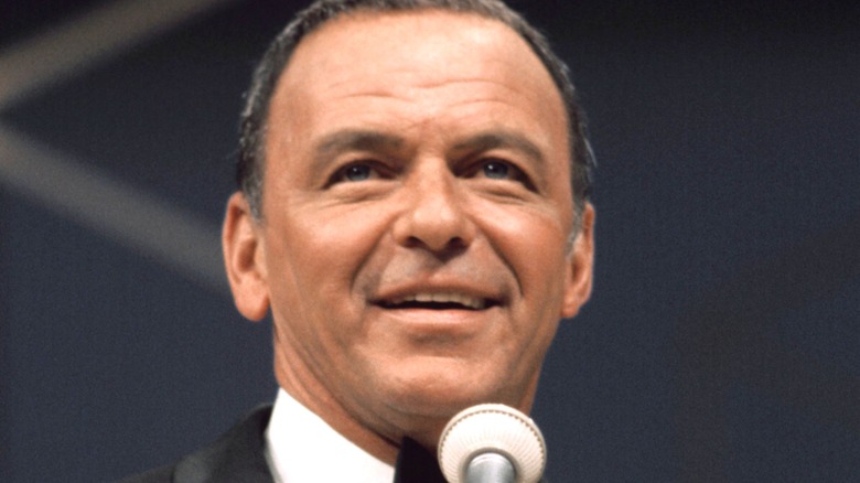 Frank Sinatra smiles onstage with a microphone