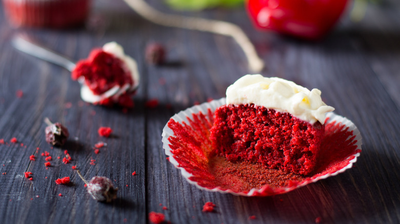 A cut in half red velvet cupcake with white icing
