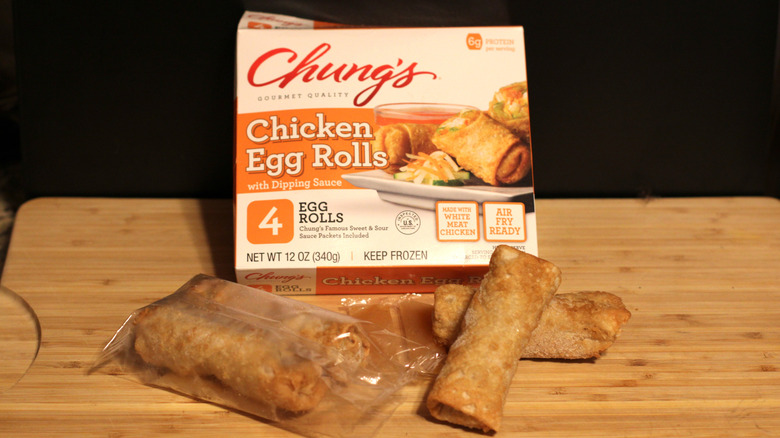 An empty box of Chung's chicken egg rolls alongside its contents displayed on a cutting board