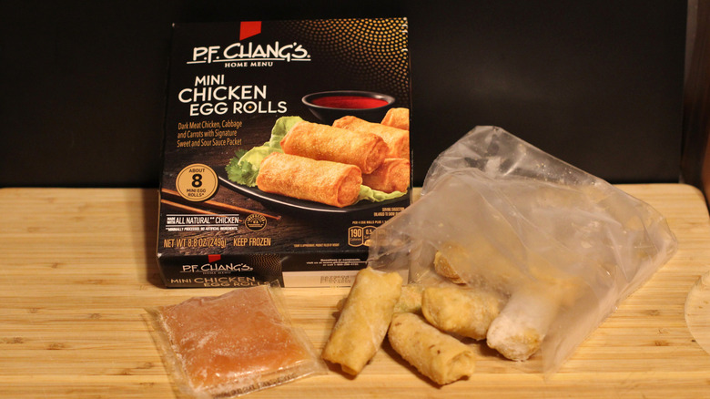 An empty box of P.F. Chang's mini chicken egg rolls alongside its contents displayed on a cutting board