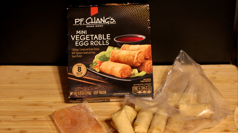 An empty box of P.F Chang's mini vegetable egg rolls alongside its contents displayed on a cutting board