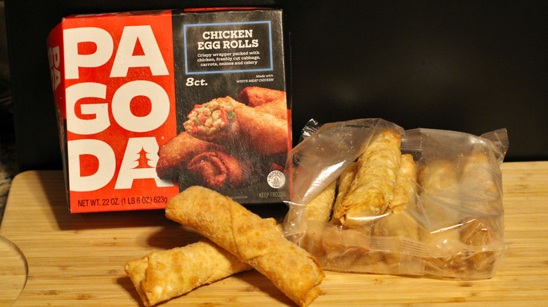 An empty box of Pagoda chicken egg rolls alongside its contents displayed on a cutting board