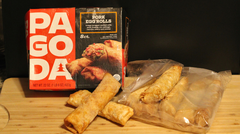 An empty box of Pagoda pork egg rolls alongside its contents displayed on a cutting board
