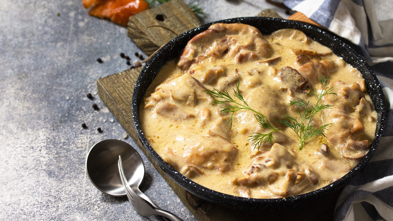A bowl of chicken stew in a black bowl on a cutting board