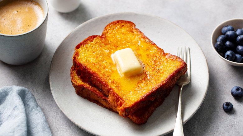 French toast topped with butter and served with coffee and berries.