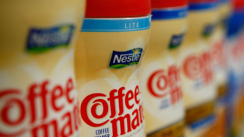 Containers of Nestle Coffee Mate coffee creamer are displayed on store shelf.