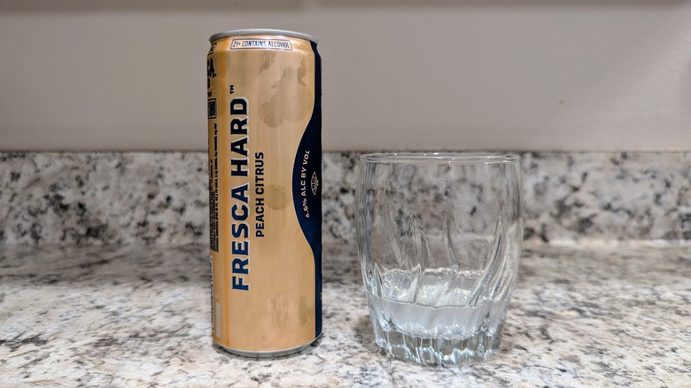 Peach Citrus Hard Fresca on counter with glass.