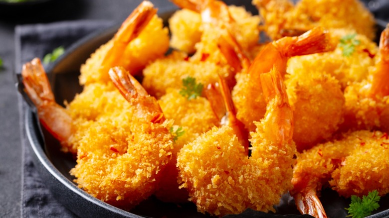 Several pieces of fried shrimp on a black plate