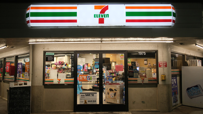 The entrance of a 7-Eleven illuminated at night