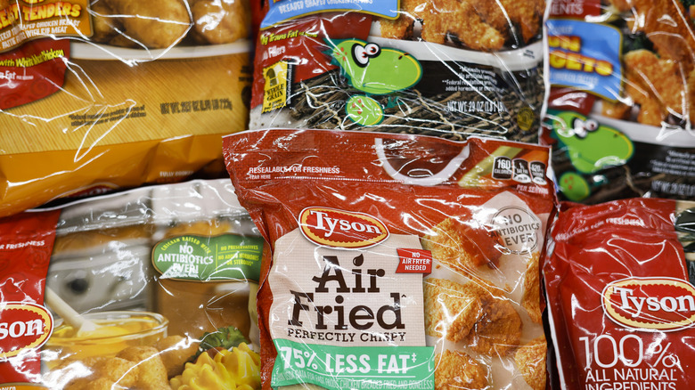 Multiple bags of frozen bagged chicken laying down in a freezer.