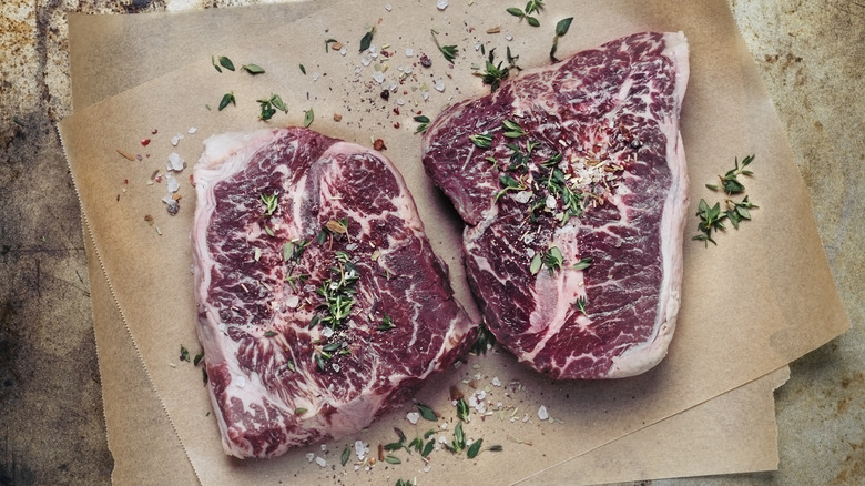 Two seasoned raw steaks on parchment paper