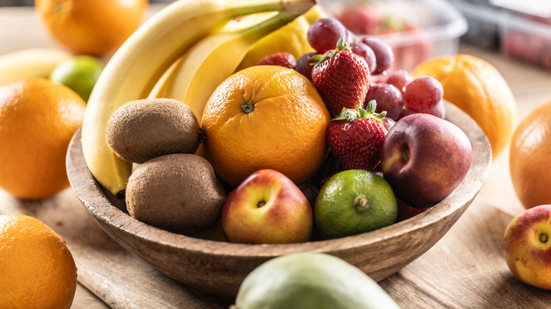 Assorted fruit in a wooden bowl on a wooden surface