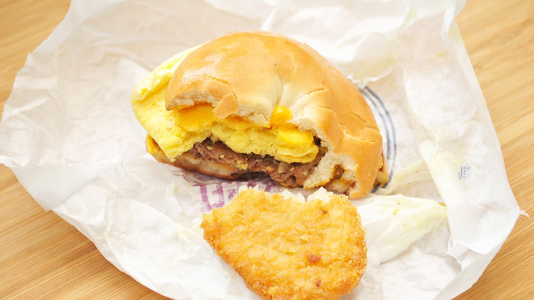 A bagel breakfast sandwich half eaten with a half eaten hash brown