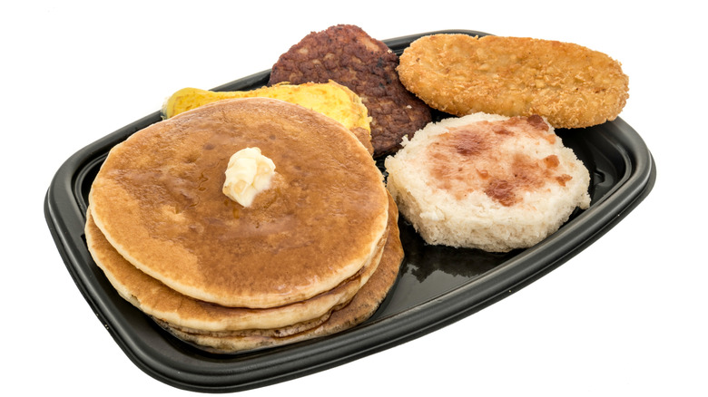 A Big Breakfast at McDonald's platter with three pancakes, a biscuit, sausage, eggs, and a hash brown
