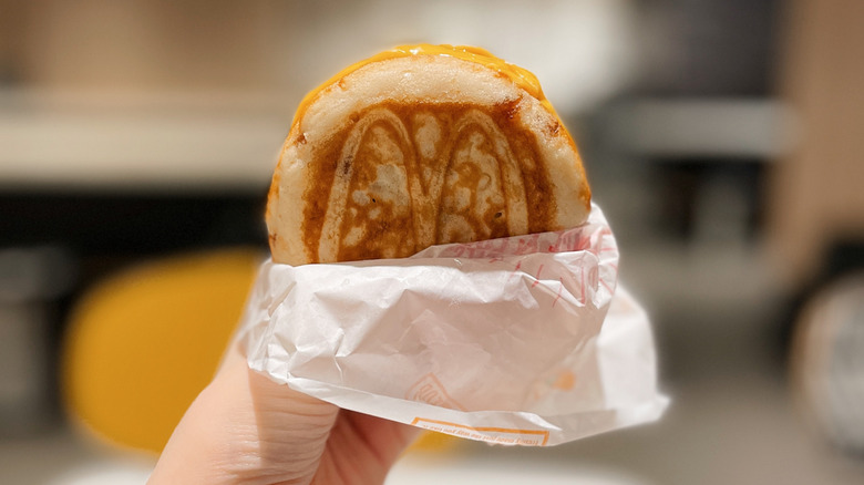 A person holding a McGriddle sandwich in a wrapper