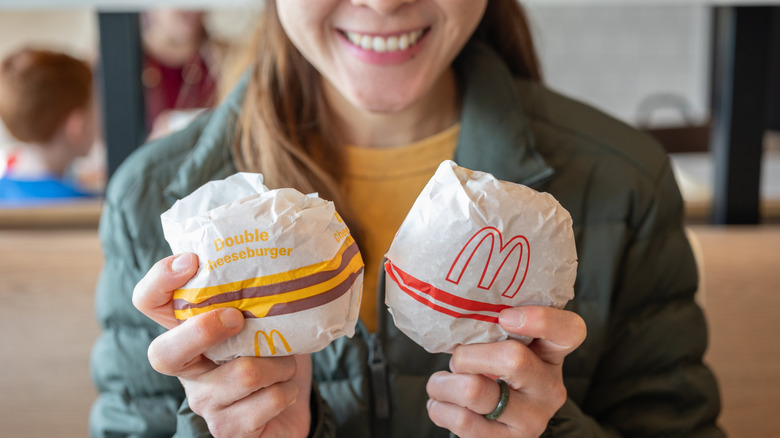 A person holding two sandwiches in wrappers from McDonald's